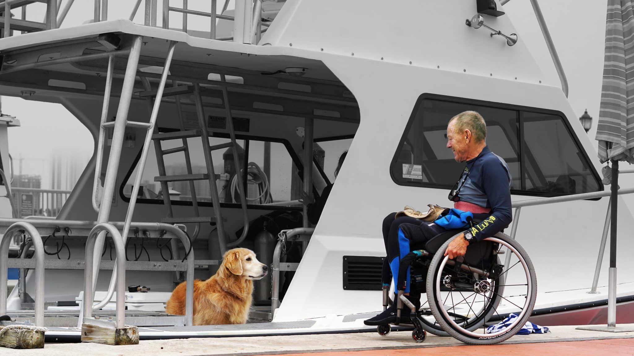 A girl and her service dog smile on the beach.