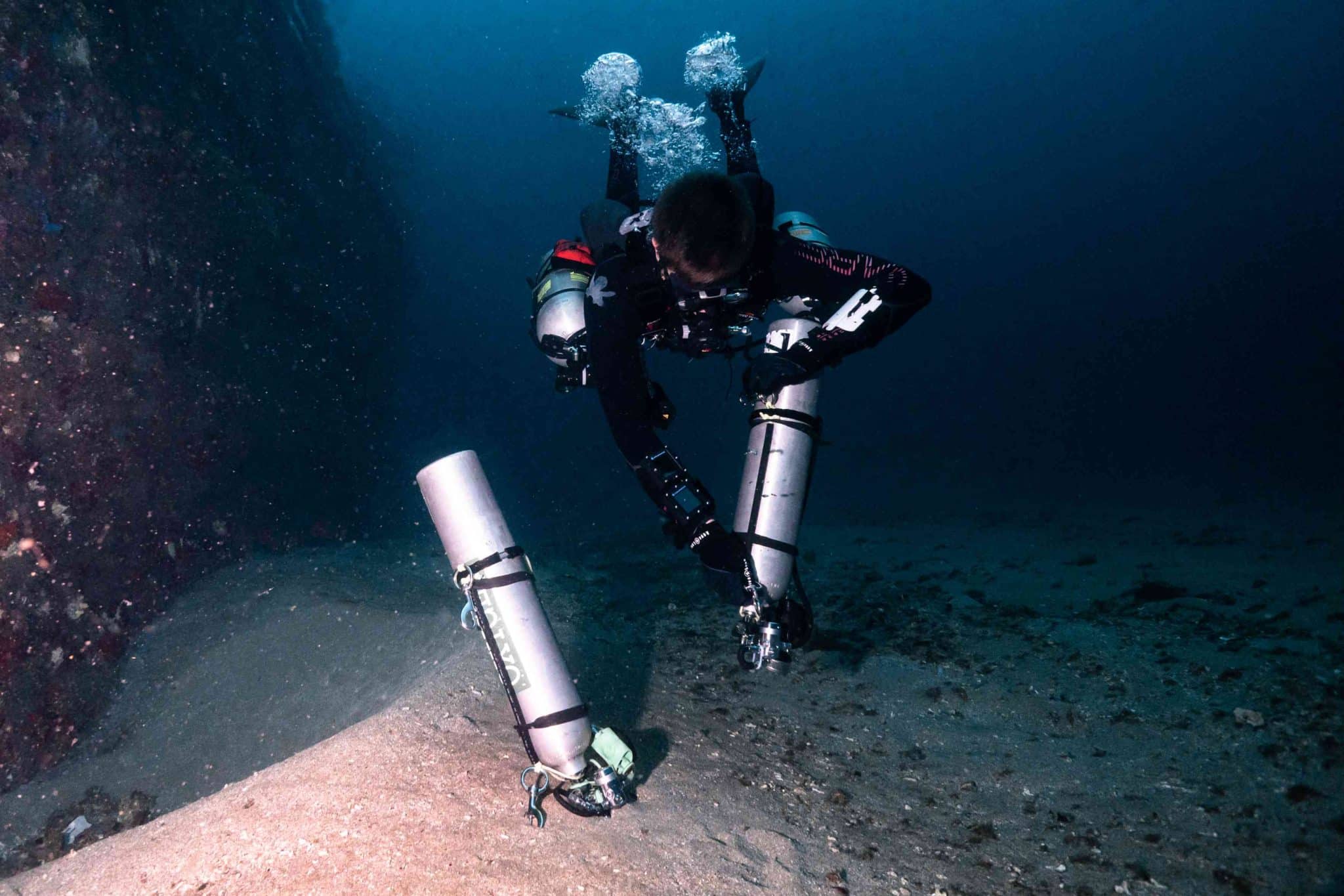 A diver donning deco bottles underwater, a skill practiced in the Tec Deep Course