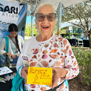 A woman holds up a decorated drift card and smiles